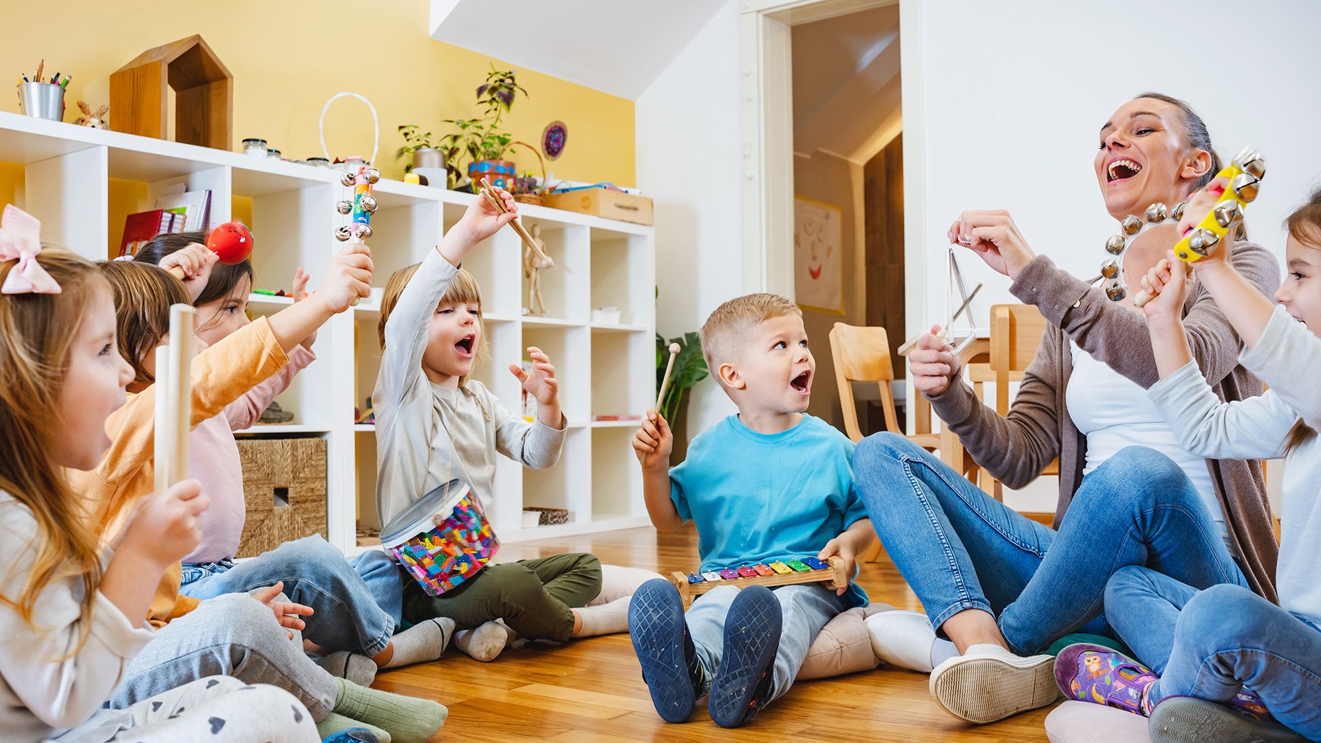 Erziehering musiziert mit ihrer Gruppe von Kindern