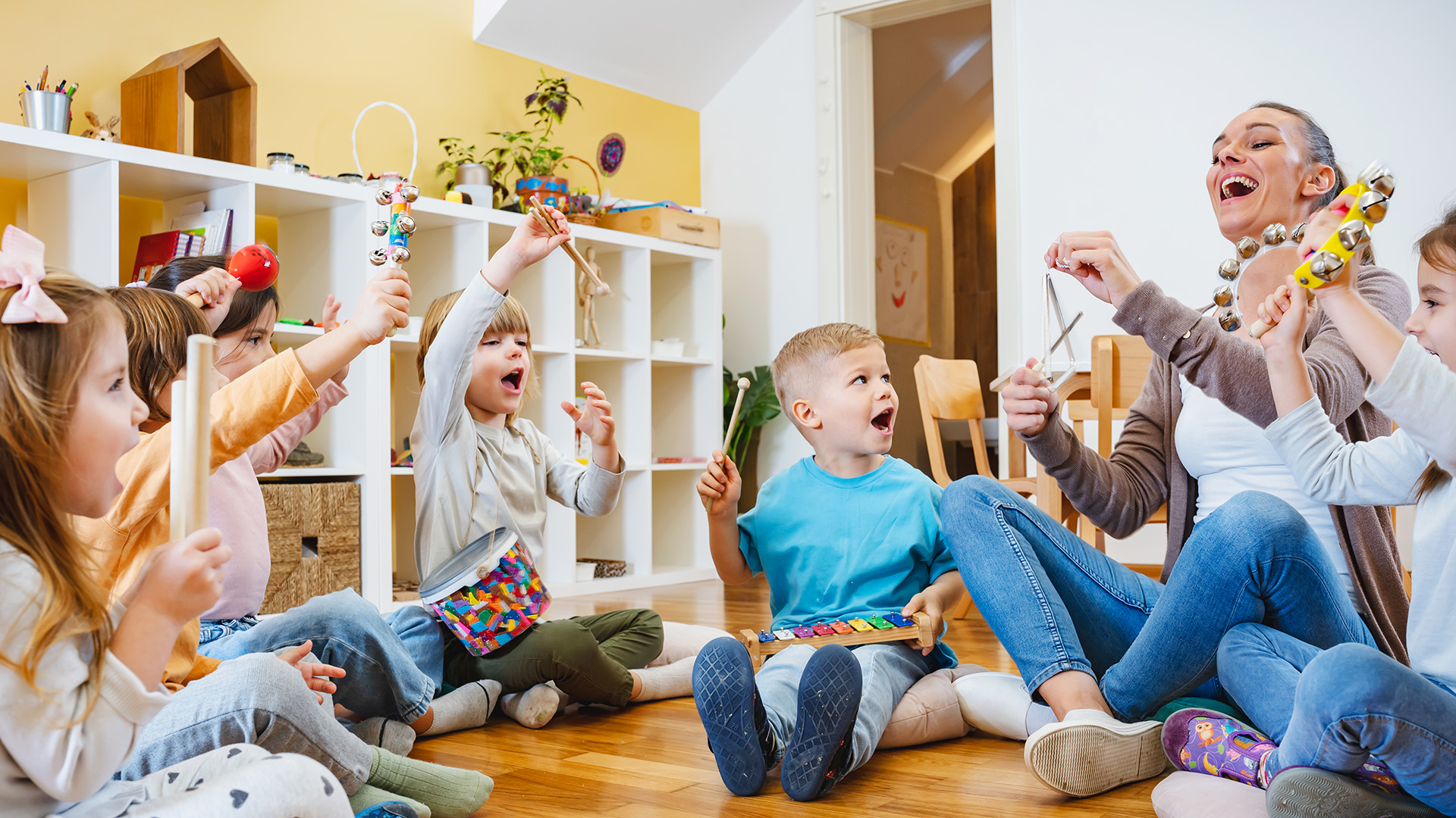 Erzieherin musiziert mit ihrer Gruppe von Kindern